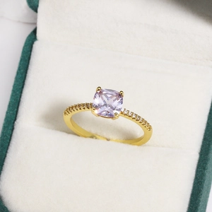 Macro shot of a lavender cushion-cut gemstone ring with a gold diamond-encrusted band