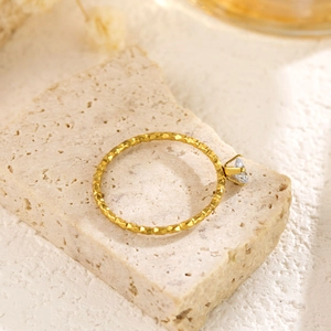 Close-up of a hammer-textured 18k gold ring with a single zircon in a six-prong setting