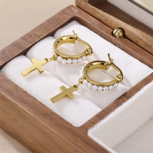 Goldene Creolen mit Perlen und minimalistischem Kreuzanhänger auf Schmuckdisplay