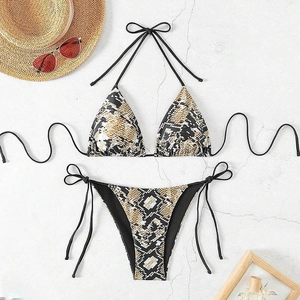 Detailed flat lay of snake print bikini with black ties and stylish beach accessories