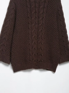 Detail of chunky cable knit texture on deep coffee brown oversized sweater fabric