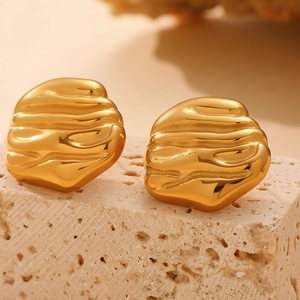 Golden geometric earrings with vintage lava texture on a natural stone background