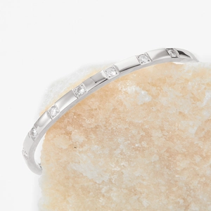 Polished stainless steel bangle with inlaid round zircon set on a textured stone base