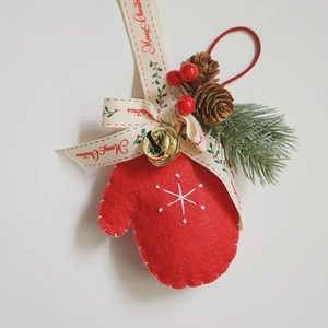 Detail of red wool felt Christmas glove ornament with golden bell and pine cone