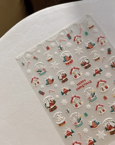 Gros plan d'autocollants 5D de Noël pour ongles avec boules de neige et maisons