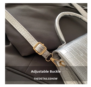 Close-up of silver crocodile pattern bag with gold adjustable buckle on suit fabric