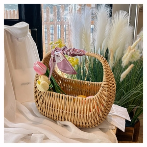 Detail of hand-woven rattan basket bag with decorative silk scarf and spring tulips