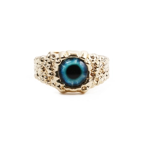 Macro shot of punk style golden ring featuring a detailed blue glass eyeball center