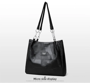 Detail showing the geometric patchwork texture and leather chain strap of the black tote bag