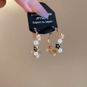 Detail of floral hoop earrings with pink blue petals and pearls on a display card