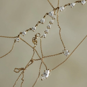 Detail of gold zircon necklace with marquise and teardrop cuts on warm grey background