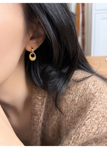 Detail goldener Creolen mit mattiertem Anhänger, getragen von einem Modell im Profil