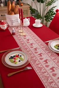 Detail of red knitted Christmas table runner with white deer and snowflake patterns