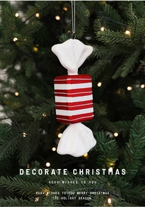 Close-up of red and white striped candy Christmas ornament with glitter finish on a tree