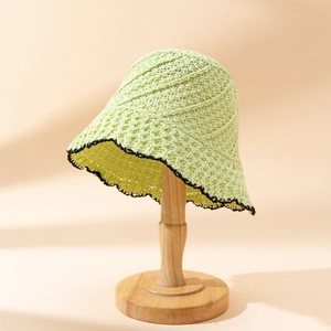 Chapeau bob en maille verte pour femme avec bord festonné noir sur support bois