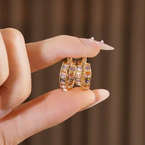 Vintage gold hoop earrings with colorful rainbow gradient gemstones held by hand