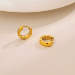 Polished 18K gold minimalist stainless steel bevelled hoop earrings on warm surface