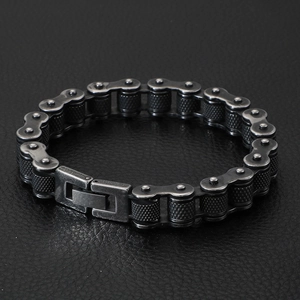 Detailed close-up of a vintage industrial biker chain bracelet on black leather background
