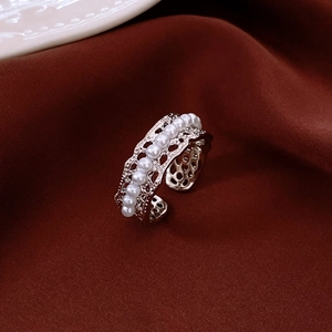 Detailed macro view of 18K gold plated pearl hollow ring on red silk fabric texture