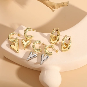 Detailed shot of gold heart pendant hoop earrings displayed on a beige stand