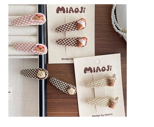 Detailed close-up of colorful checkered fabric hair clips with cute cartoon patches