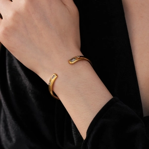 Close-up of gold water-drop zircon open cuff bracelet on model with black velvet background