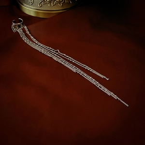 Macro shot of silver metal tassel ear cuff with fine long chains on deep red fabric