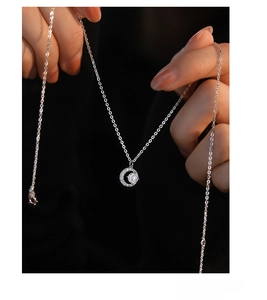 Macro detail of S999 sterling silver moon necklace with a sparkling zircon stone pendant