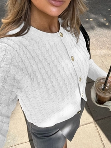 Detail of white cable knit cardigan with vintage golden buttons and textured patterns