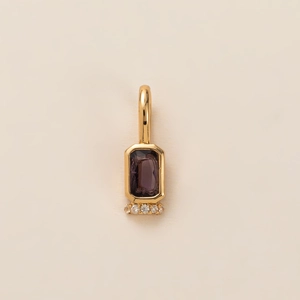 Detailed view of a gold pendant featuring a rectangular purple gemstone with four accent diamonds