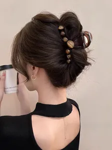 Detail view of large amber gradient bead hair claw clip styled on woman's updo hairstyle