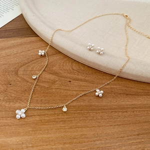 Detail of gold floral necklace and stud earrings set with white pearls and crystals
