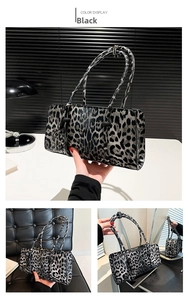 Detail of black and white leopard baguette bag with heart pendant and twin straps