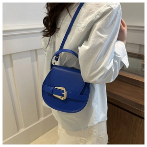 Detail view of a blue PU leather saddle bag featuring a large gold buckle on the shoulder strap