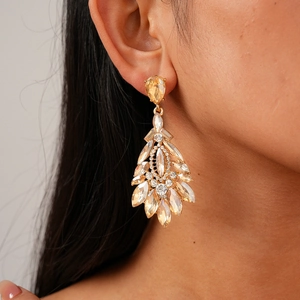 Macro shot of champagne gold drop earrings with inlaid crystals on female model