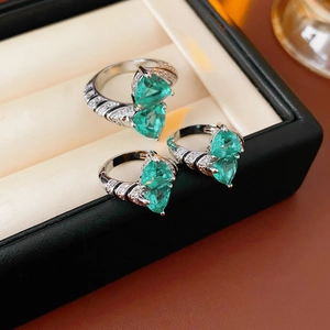 Macro shot of three silver rings featuring heart-shaped green stones and micro-paved zircons