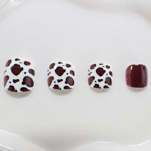 Square toe press-on nails with red-brown cow print and solid glossy finish