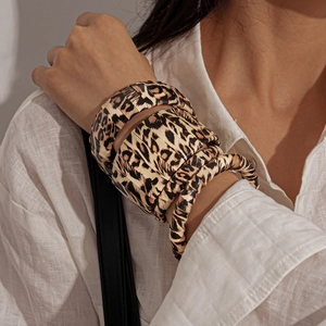 Close-up of leopard print textured bangles set worn against a neutral linen shirt fabric