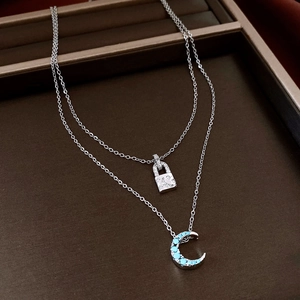 Détail du collier double rang argenté avec cadenas étoile-lune et croissant de pierre bleue