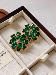 Detailed macro view of vintage gold flower earrings with emerald green zircon cubes