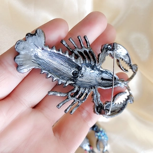Vintage lobster brooch with rhinestones on champagne satin background for suits