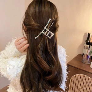 Silver wavy metal hair claw clip worn on long wavy hair for an elegant half-up style