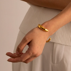 Bracciale rigido aperto in acciaio inossidabile placcato oro 18k sul polso del modello