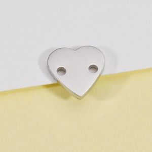 Gros plan de pendentifs en forme de cœur en acier poli avec deux trous pour bijoux DIY