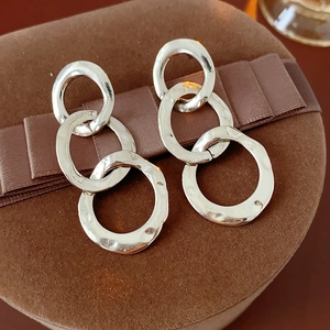 Close-up of silver interlocking hoop earrings with textured finish on a velvet gift box