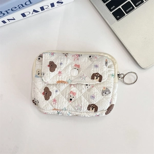 Detail of white quilted pouch with cute puppy patterns and zip closure on white desk