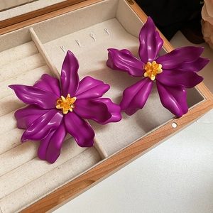 Detailed view of purple acrylic flower earrings with beaded centers in a wooden box