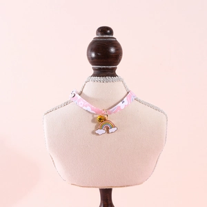 Detail of pink floral pet collar with rainbow charm and bell on display stand