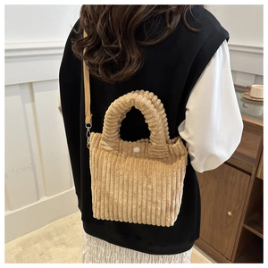Detail of corduroy bucket bag showing plush texture and adjustable canvas strap