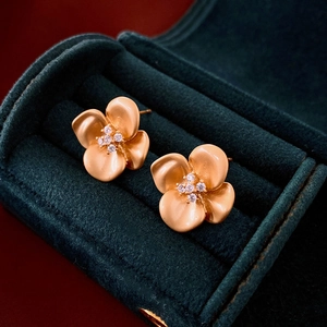 Macro view of gold flower earrings with zircon centers on dark green velvet